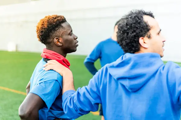 Bir futbol sahasında antrenman yapan bir grup melez genç. Genç atletler ve koçlardan oluşan bir takım futbol sahasında birlikte antrenman yapıyor.
