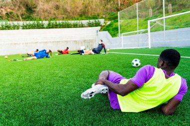 Bir grup Afrikalı siyahi genç futbol sahasında antrenman yapıyor, futbol oynuyor ve spor yapıyor. Genç sporcular ve koçlardan oluşan bir takım bir futbol sahasında birlikte antrenman yapıyor.