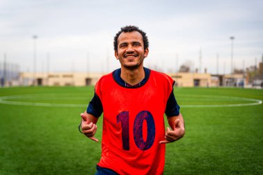 Açık hava futbol sahasındaki genç Arap futbolcunun portresi. Futbol sahasında spor ve egzersiz yapan umut dolu genç bir göçmen sporcu.