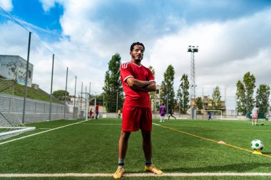 Açık hava futbol sahasındaki genç Arap futbolcunun portresi. Futbol sahasında spor ve egzersiz yapan umut dolu genç bir göçmen sporcu.