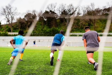 Bir grup Afrikalı siyahi genç futbol sahasında antrenman yapıyor, futbol oynuyor ve spor yapıyor. Genç sporcular ve koçlardan oluşan bir takım bir futbol sahasında birlikte antrenman yapıyor.