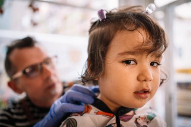 Bebek ilk kez saçını kestiriyor. Kuaför kuaför kuaförde Latin bir kızın saçını kesiyor.