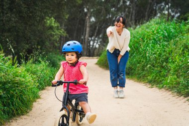 Küçük kız annesinin yardımıyla dışarıda bisiklete binmeyi öğreniyor. Büyüyen ve gelişen bebek kavramı, anne kızının açık havada birbirine bağlanması.