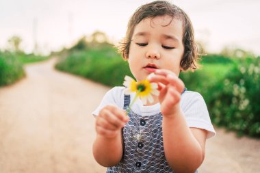 Küçük kız bahar aylarında açık havada papatya topluyor. Çiçek topluyor, doğanın tadını çıkarıyor. Kırsalda faaliyet kavramı ve çocukluğun tadını çıkarıyor.