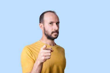 Genç adam kamerayı ciddi bir özgüven ifadesiyle işaret ediyor.