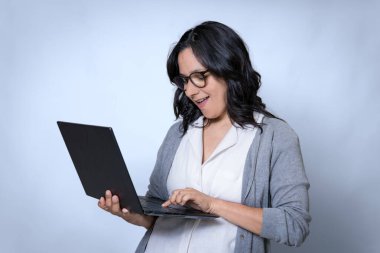 40 'larında Latin kökenli genç bir iş kadını elinde dizüstü bilgisayarla online işlerde çalışıyor, profesyonel genç bayan girişimci.