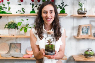 Çiçekçisinde teraryumla poz veren genç kadın portresi. Küçük işletme sahibi ve kadın girişimci kavramı