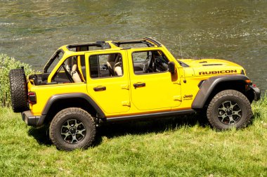 Dağ nehrinin yakınına park edilmiş sarı bir cip.