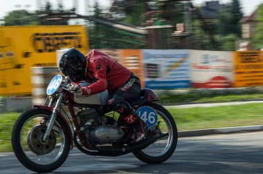 Motosikletli adam sokakta motosiklet sürüyor.