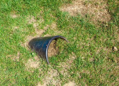 Çimlerin üzerinde büyük siyah bir metal boru.