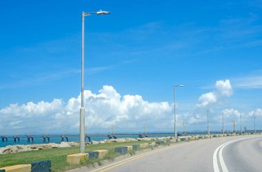 Doğal manzara arka plan, köprü, yol, sokak lambaları, beyaz bulutlar ve deniz