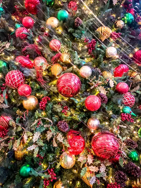 Dikey Noel ağacı süslemeleri yeşil, altın ve kırmızı toplarla yakın plan