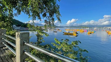 Balıkçılık, körfezdeki eğlence tekneleri, ağaçlı, bulutlu, mavi gökyüzü ve dağlı doğal arka plan.