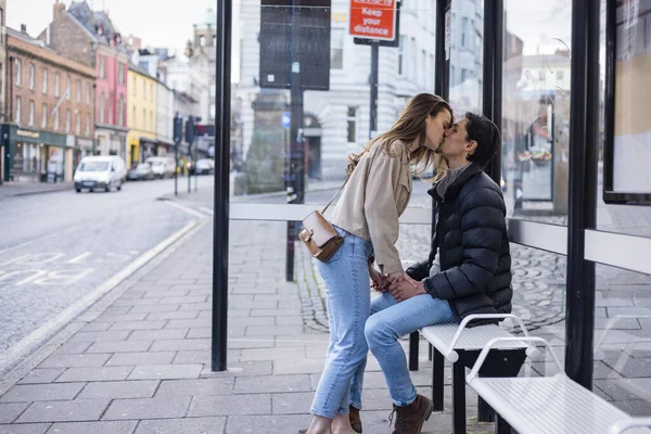 バスの停留所で一緒に待っている若いカップルの横ビューショット 彼らは愛にあり キスを共有 ロイヤリティフリーのストック写真
