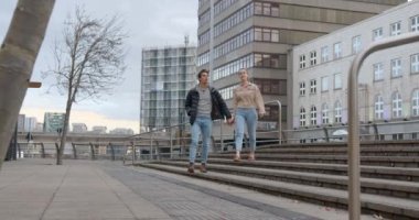 Yan yana yürüyen genç bir çiftin geniş açılı görüntüsü. El ele tutuşuyorlar ve birbirlerine aşıklar..