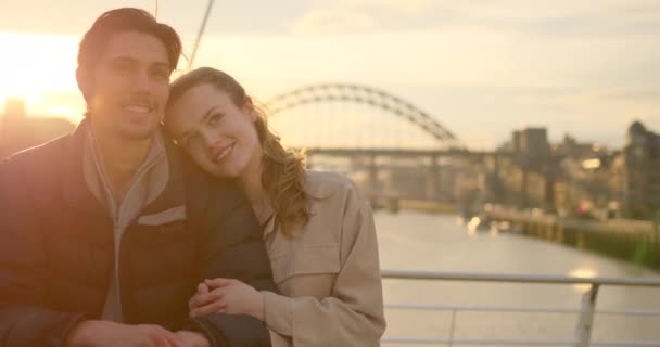 ニューカッスル アポン タインで一緒に過ごした若いカップル 彼らは橋の上に立っている彼らの後ろに川のタインでお互いを受け入れながらキス — ストック動画