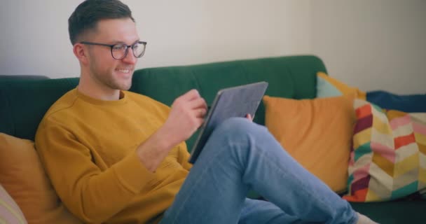 Dijital Tablet Kullanarak Kanepede Oturan Adam Çevrimiçi Ticarette Çalışıyor — Stok video