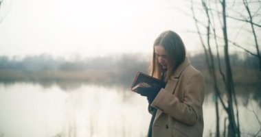 Parkta kitap okuyan düşünceli ve sıkıntılı bir kadının portresi.