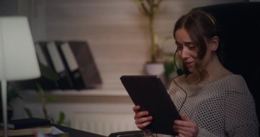 Kulaklık takmış meşgul bir iş kadını müşterisiyle konuşuyor, profesyonel bir tavır sergiliyor ve yüksek kalitede müşteri hizmetleri sağlıyor..