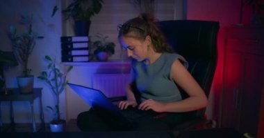 Odaklanmış bir kadın dizüstü bilgisayarının önünde oturuyor ve kendini bilişim programcısı olarak işine veriyor..