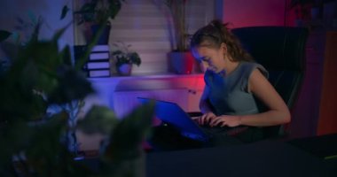 Odaklanmış bir kadın dizüstü bilgisayarının önünde oturuyor ve kendini bilişim programcısı olarak işine veriyor..