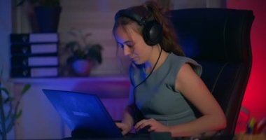 Odaklanmış bir kadın dizüstü bilgisayarının önünde oturuyor ve kendini bilişim programcısı olarak işine veriyor..