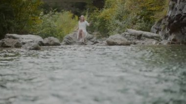 Kadın heybetli bir dağ şelalesinin önünde duruyor, büyüleyici güzelliğini ve gücünü içine çekiyor.