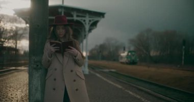 Tren istasyonundaki düşünceli ve düşünceli kadın kendi düşüncelerinde kaybolmuş, derin düşüncelere dalmış ve yansımasına dalmış.