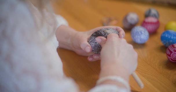 文化的 宗教的な伝統であるイースターエッグを飾る女性複雑なデザインと象徴的なイメージを持つ卵を慎重にペイントし 飾るさまざまな技術を使用しています — ストック動画