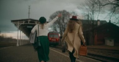 İki arkadaş tren istasyonundan ayrılan trene yetişmek için acele ediyor.