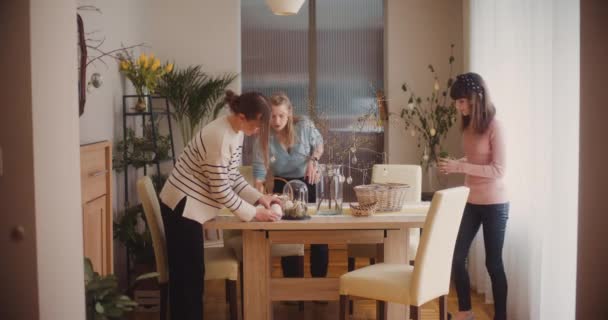 イースター休暇のためのテーブルを飾る姉妹 イースターエッグとイースターデコレーション — ストック動画