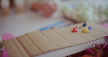 Dikkatli bir hassasiyetle, sanatçı tüpten beyaz boya akışını ustalıkla sıkıyor ve onu boyacı paletine aktarıyor.