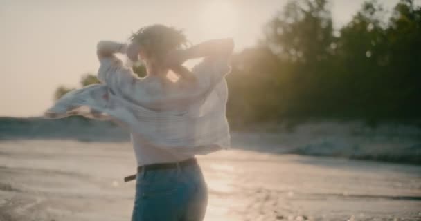 ビーチで純粋な肯定と至福を経験し 日没時に黄金の太陽の光の中で優雅に舞う放射性と喜びの女性 — ストック動画