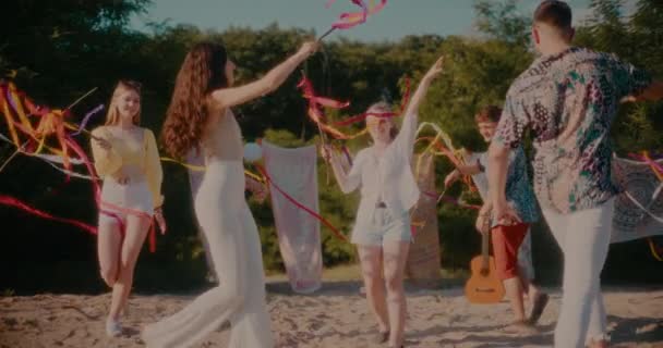晴れた日にビーチでリボンを楽しみながら踊る幸せな若い男性と女性の友人のスローモーションショット — ストック動画