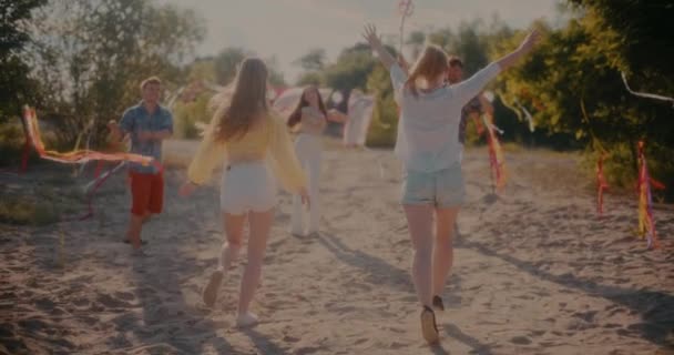 ビーチでの週末のパーティー中にリボンで踊る友人に向かって走っている女性のスローモーションショット — ストック動画