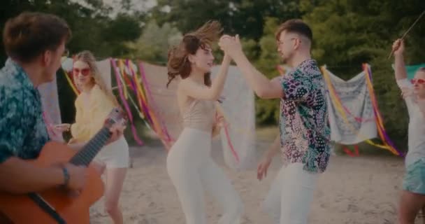 해변에서 파티를 즐기는 친구들에게 둘러싸여 부부가 춤추는 의느린 — 비디오