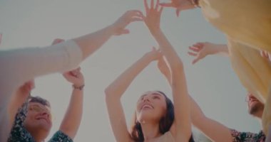 Mutlu genç kadın ve erkeklerin kollarıyla gökyüzüne doğru yükselen düşük açılı görüntüsü