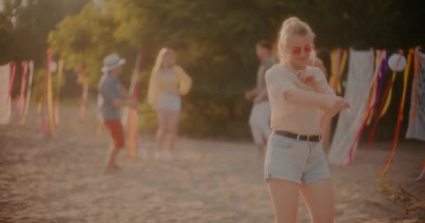 Wesoła Blondynka Okularach Przeciwsłonecznych Tańcząca Przeciwko Przyjaciołom Cieszącym Się Plaży — Wideo stockowe