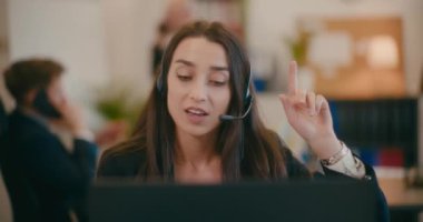 Ofisteki dizüstü bilgisayardan kadın müşteri temsilcisinin kulaklık videosuyla yavaş çekim yapması..