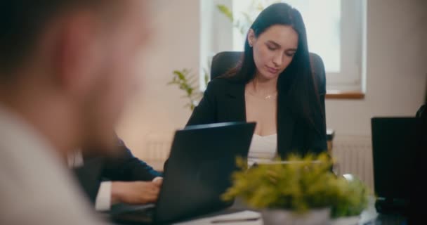 オフィスの同僚と座っている間 デジタルタブレットを使用して深刻な若い女性マネージャー — ストック動画