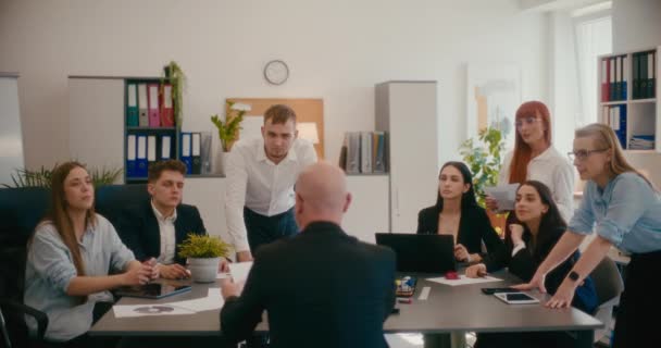 オフィスでの会議中にチームに文書を与える男性マネージャーのスローモーション — ストック動画