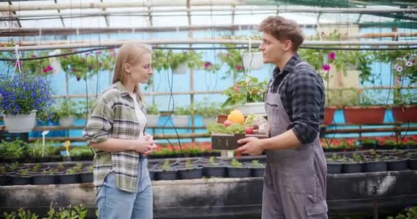 温室で働いている間収穫された野菜を同僚に与える男性農民のゆっくりとした動き — ストック動画
