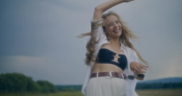 快乐的女人举着太阳镜在田野里与天空共舞的慢镜头 — 图库视频影像