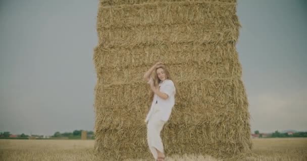 无忧无虑的年轻女子在田野的天空中在干草前跳舞的慢镜头 — 图库视频影像