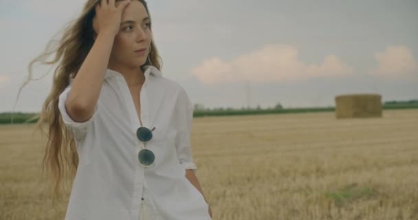 沉思的年轻女子手牵着头发站在田边做白日梦的慢镜头 — 图库视频影像
