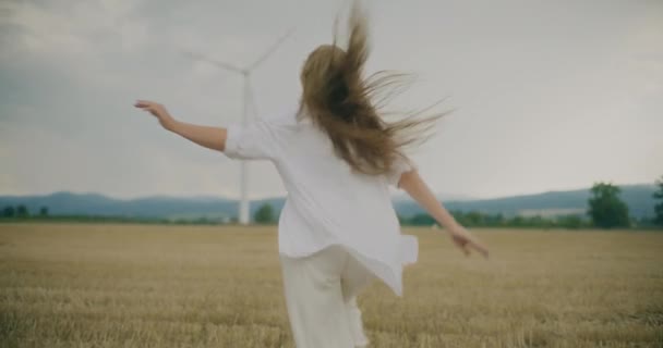 空に向かってフィールドで走る陽気な若い女性のスローモーションリアビューショット — ストック動画