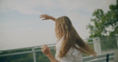 Yavaş çekim, kaygısız genç kadın, sarı saçlar gökyüzünde dans ediyor.