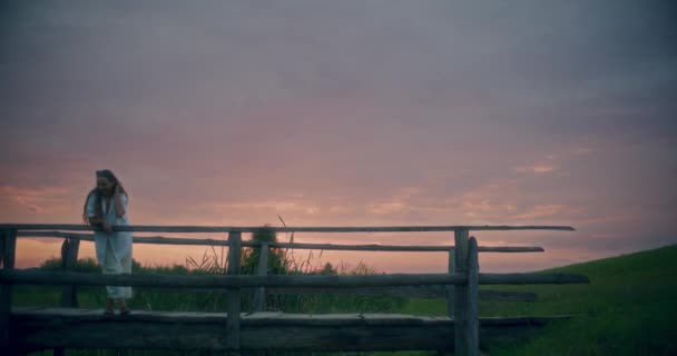 一个微笑的女人在黄昏时站在桥上与天空抗衡的慢镜头 — 图库视频影像