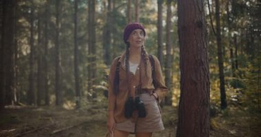 Yaz tatilinde ormanı keşfederken etrafa bakıp gülümseyen genç bir kadın.