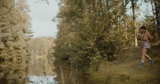 Χαρούμενη Νεαρή Γυναίκα Τρέχει Στο Γρασίδι Από Λίμνη Ενώ Εξερεύνηση — Αρχείο Βίντεο